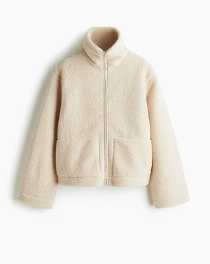 Beige teddyjacka med dragkedja - Mysig beige teddyjacka med hög krage och hel dragkedja framtill. Jackan har två stora fickor och är tillverkad i fluffigt teddy-material som håller dig varm och stylish. Perfekt för kyliga dagar och enkel att matcha med det mesta. 