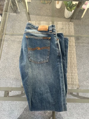 Nudie Jeans Skinny Lin Easy Strikey W34 L34 - Säljer ett par Nudie Jeans Skinny Lin i tvätten Easy Strikey, storlek W34 L34. Tight passform med stretch (98% ekologisk bomull, 2% elastan) och snygg blå denim med naturlig fading. Klassisk Nudie-kvalitet, i fint använt skick utan hål eller större slitage. Perfekta för dig som vill ha bekväma slim fit-jeans med bra passform.
