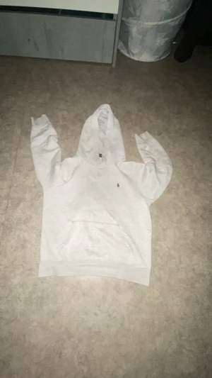 Grå hoodie från Polo Ralph Lauren - Vit hoodie från Polo Ralph Lauren med klassisk blå broderad logga på bröstet. Tröjan har huva, magficka och långa ärmar. Mjuk insida äkta pris kan diskuteras 