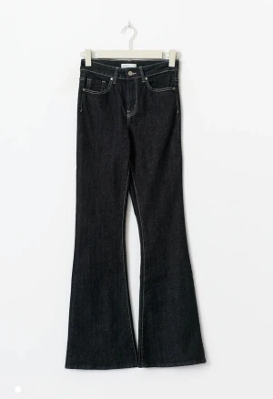 Mörkblå high waist flare jeans Rino petite - Snygga mörkblå jeans med hög midja och flare-ben från Gina tricot. Klassisk femficksmodell med kontrastsydda sömmar och knappstängning. Perfekt för dig som gillar retrovibbar och vill ha en cool siluett. Materialet är slitstarkt jeans och modellen är petite. Helt nya med prislappar kvar fram och bak. 