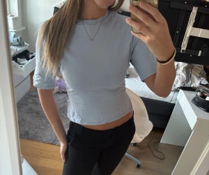 Slutsåld Ljusblå Nelly topp  - Säljer min ljusblå Nelly topp som är helt slutsåld i denna färg, med korta ärmar och snygg öppen rygg som knyts med en rosett. T-shirten har en enkel, stilren design och är perfekt för dig som gillar trendiga detaljer. Materialet känns mjukt och lätt mot huden.