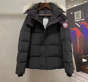 Svart dunjacka från Canada Goose - Säljer en svart dunjacka från Canada Goose med pösig passform och klassisk patch på ärmen. Jackan har huva med vit fuskpäls, dragkedja och knappar framtill samt långa ärmar. Perfekt för kalla dagar när du vill hålla stilen.