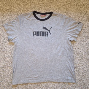 Grå Puma t-shirt - Snygg grå t-shirt från Puma i storlek XXL men skulle nog säga den passar mer som XL/L. Använd fåtal gånger och inga defekter finns på tröjan. Den har lite creasningar men det går bort enkelt med llite strykning. Skick: 8/10