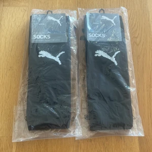 Svarta fotbollsstrumpor Puma - Svarta knälånga fotbollsstrumpor från Puma med vit Puma-logga på framsidan. Snygg och sportig design som passar perfekt till fotbollsträningen. Strumporna är tillverkade i ett mjukt och slitstarkt material som sitter skönt på benet. 