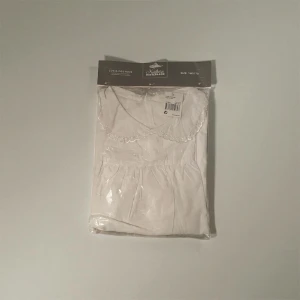 Vit luciaklänning från Northern Winterland - Klassisk vit luciaklänning med söt spetskantad krage från Northern Winterland. Perfekt för luciatåg och högtider. Klänningen har lång ärm och är tillverkad i bomull för en bekväm känsla.