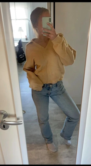 Beige stickad v-ringad tröja - Mysig beige stickad tröja med v-ringad hals och långa ärmar. Tröjan har ribbade muddar vid ärmslut och en loose passform som ger en chill vibe. Perfekt att slänga på sig när det är lite kyligt ute. Små svarta fläckar vid ärmen, men de märks inte🥰