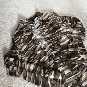 Cool camoflauge jacka/kofta🪖 - Säljer denna coola och unika camoflauge jacka med en guldstjärna på bröstet och knappar längs magen som sitter där för utseendet. Koftan är i storlek S och sitter som en S! Kan gå ned i pris vid snabb affär!