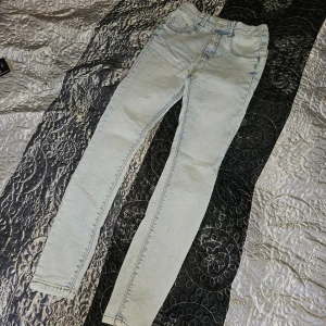 Ljusblå skinny jeans i storlek 26 - Säljer ett par ljusblå skinny jeans från FB sister i storlek 26. Jeansen har klassisk femficksdesign, bälteshällor och en snygg ljus tvätt. Perfekta för dig som gillar en tight passform och stilren look.