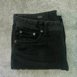 Svarta jeans från Jack&Jones - Svarta jeansbyxor från Jack&Jones i modellen Regular Clark. Klassisk femficksdesign, raka ben och normal passform. Jeansen är tillverkade i ett slitstarkt bomullstyg och har svarta detaljer. Perfekta för en clean och stilren look.