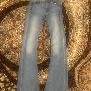 Bootcut ljusblå jeans - Säljer ett par ljusblå jeans med bootcut-snitt. Byxorna har klassisk femficksdesign och är tillverkade i jeansmaterial. Passformen är normal och de har en snygg tvättad look som ger en avslappnad vibe.