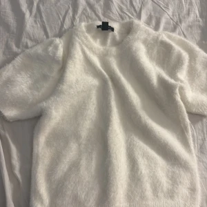 Vit fluffig tröja från New Look - Supermjuk och fluffig vit tröja från New Look med korta ärmar och rund hals. Tröjan har en mysig pälsliknande känsla och är perfekt för dig som vill ha en söt och trendig look. Passar lika bra till jeans som till kjol.
