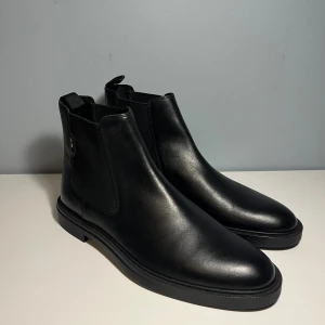 BOSS Chelsea Boots - BOSS Calev Leather Chelsea Boot Black Storlek 44 Tillverkade i Portugal Aldrig använda, beställde två storlekar och glömde returnera. Ordinarie 2699 kr https://www.careofcarl.se/sv/boss-black-calev-leather-chelsea-boot-black-2?channable=0414106964003239333739343134e0&utm_source=google&utm_medium=cpc&utm_campaign=S%20/%200%20/%20Category%20/%20Shoes&gad_source=1&gad_campaignid=22251853809&gclid=Cj0KCQjw9JLHBhC-ARIsAK4Phcpv4_FPEy9IB-ZRM5FgSiy93TdMLkI_JcksREAH4NHWkN6MKFCNwaYaAh6iEALw_wcB