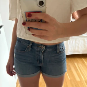 Levi’s jeansshorts - Snygga blå jeansshorts från Levi's Premium med klassisk femficksdesign, uppvikta benslut och slitna detaljer framtill. Shortsen har normal passform och är tillverkade i mjukt jeanstyg med läderpatch bak. Storlek 26 och true to size (motsvarar s/m)🤗