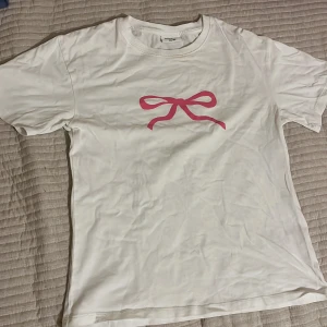 Vit t-shirt med en rosa rosett - Aldrig blivit använd så bra sick.