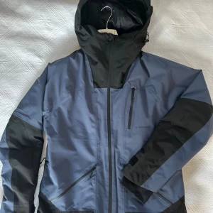 Blå och svart skidjacka från Everest - Säljer en blå och svart skidjacka från Everest stl M. Jackan är fodrad, utrustad med andningsbara fickor, samt en liten ficka för liftkortet på högerarmen. Endast använd en vecka under sportlovet och i ett mycket gott skick. Nypris 650 kr.