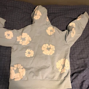 Ljusblå hoodie från Denim Tears S - Säljer en ljusblå hoodie från Denim Tears med unika vita blommönster över hela tröjan. 