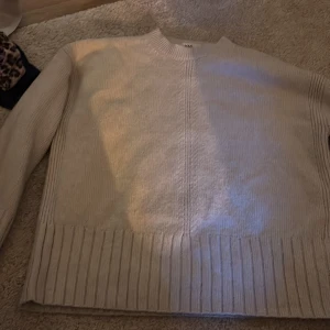 Beige stickad tröja från M&S - Säljer en beige stickad tröja från M&S i storlek S. Tröjan har ribbade muddar, diskret kabelstickad detalj mitt fram och långärmad modell. Perfekt för lager-på-lager och chill höst- eller vinterstil.