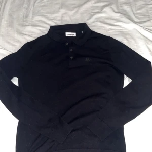 Svart pikétröja från J.Lindeberg - Klassisk svart pikétröja från J.Lindeberg med lång ärm och krage. Skönt och luftigt material som är väldigt flexibelt storlek M men passar även S