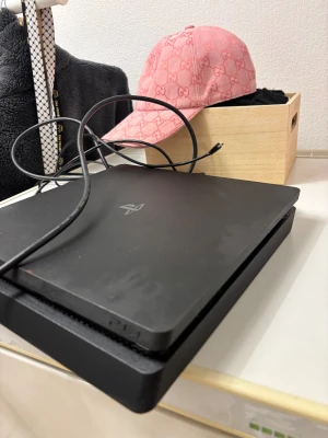 PlayStation 4 Slim - Sony PlayStation 4 Slim i svart färg. Den är i gott skick och fungerar som den ska. HDMI-kabel och strömkabel medföljer. Perfekt för gaming och underhållning hemma.