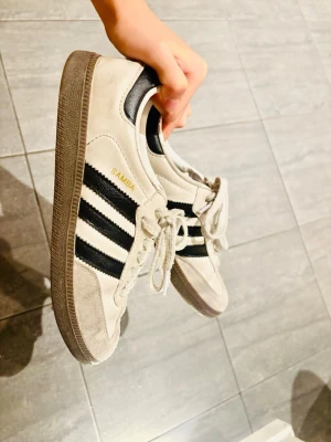 Adidas Samba sneakers i vitt och svart - Såå snygga adidas sambas, matchar med alla möjliga outfits. Passar perfekt för mig som har strl 39/40. Den har använts väl men frf i god skick! Det enda lilla är att innersulan har slitits lite men det påverkar ingenting alls och känns inte!