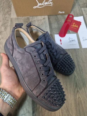 Grå Christian Louboutin sneakers med nitar - Som nya! Box, kort, dustbag och även skohorn medföljer. Storlek: 42 Populär färg, passa på innan de säljes.  Skriv vid frågor eller funderingar!