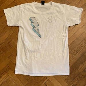Bvaldi t shirt - Vit t-shirt från Bvaldi i bomull med korta ärmar. På bröstet finns en stor blixt i blå och silverfärgad strass samt bokstäverna 'BV' i strass. Perfekt för dig som gillar statement-plagg och bling.