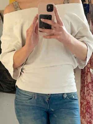 Vit offshoulder topp - Säljer en vit offshoulder topp med trekvartsärm och bred halsringning. Det var från början en oversized t-shirt som jag sydde om (på amatörnivå så förvänta er inget proffesionellt verk, haha)