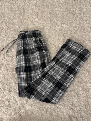 Svarta och vita rutiga mjukisbyxor - Säljer ett par mjukisbyxor med svart och vitt rutmönster, med snören och med fickor på sidorna. 