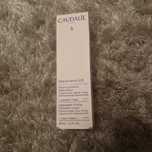 Caudalie Resveratrol-Lift ansiktskräm - Caudalie Resveratrol-Lift Lightweight Firming Cashmere Cream är en oljefri ansiktskräm med hyaluronsyra och veganskt kollagen. Förpackningen är ljusrosa med blå text och innehåller 40 ml. Produkten är vegansk och fri från parabener, mineraloljor och silikoner.