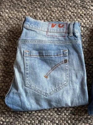 Dondup George skinny fit jeans ljusblå - Snygga ljusblå jeans från Dondup, modell George skinny fit. Klassisk femficksdesign med smal passform och diskret slitning framtill. Jeansen har knappgylf och är tillverkade i mjukt bomullsmaterial för en bekväm känsla. Perfekt för dig som gillar en modern och stilren look. 94cm