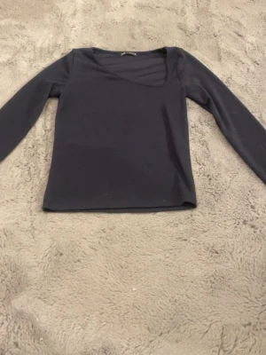 Svart långärmad topp från Zara - Säljer en stilren svart långärmad topp från Zara med mjukt material och snygg o symmetrisk hals. Perfekt att matcha med jeans eller kjol för en enkel och clean look. Toppen har en normal passform och är superenkel att bära. Kan eventuellt tänka mig gå ner i pris
