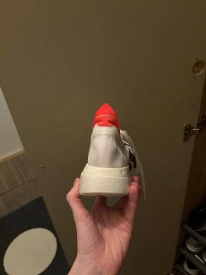 Adidas Adizero Adios Pro 4 sneakers - Säljer ett par Adidas Adizero Adios Pro 4 sneakers med vit ovandel, svarta ränder och detaljer i neonrött. Skorna har tjock, platt sula med Lightstrike Pro-teknologi och snörning. Perfekta för dig som gillar att springa snabbt och vill ha grym respons i steget.