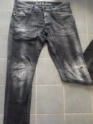 Jack and Jones slim jeans - Skick:Extremt bra.                          Storlek:36/32.                                  Beskrivning:Svarta slim fit jeans från Jack & Jones, modell Glenn. Jeansen har slitna detaljer, blekta partier och stänk för en cool, använd look. Klassisk femficksmodell med knappgylf och raka ben. Perfekta för dig som gillar streetstyle.