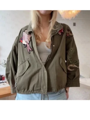 Grön h&m jacka  - Säljer en grön overshirt med broderade detaljer som fågel, orm och rosor. Jackan har snörning i midjan, stora fickor och tryckknappar. Perfekt för dig som vill ha en unik och cool look med lite army-vibe. Jättesnygg slutsåld. Pris kan diskuteras. Tryck på köp nu så försöker jag posta samma eller dagen efter❣️❣️