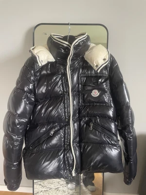 Moncler Puffer - PRISSÄNKNING - ORDP. 3299 NU 2799! Säljer en stilren och klassisk Moncler”Branson” i svart med vita detaljer. Jackan är i storlek 3 (motsvarar Medium). Det finns två små fläckar (se bild), inget som påverkar funktion eller helhetsintryck.  ✔️ Varm och bekväm ✔️ Blank finish, ikonisk Moncler-design ✔️ Original patch på bröstet ✔️ Dragkedjor och knappar i bra skick  Perfekt vinterjacka som funkar både till vardag och mer uppklätt. Hör av dig vid frågor, så svarar jag!