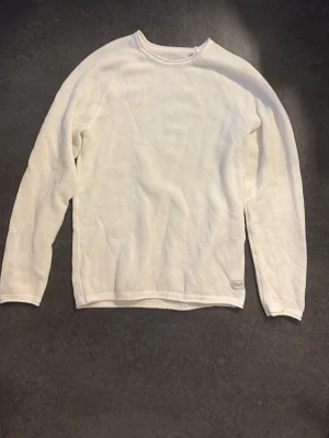 Vit stickad tröja Jack & Jones - Säljer en vit stickad tröja från Jack & Jones i storlek M. Tröjan har rund hals och är långärmad med en enkel, clean design. Materialet är mjukt och andas, perfekt för lager-på-lager under hösten eller våren. Diskret logga vid nederkanten.