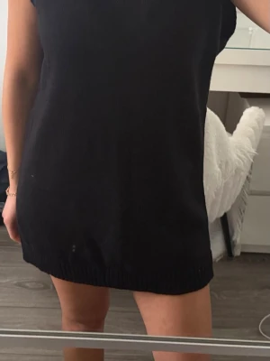 Svart stickad väst - Stickad klänning/ väst. Har haft den med kjol,  skjorta under och bälte. Används vid 1 tillfälle. 