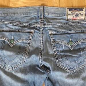 True Religion Jeans - Baggy Trueys. Lite slitna längst ner men det kan man bara klippa av. Fett coola med vita sömmar