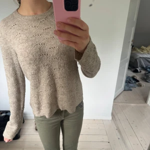 Beige stickad tröja med vågigt mönster - Säljer en beige stickad tröja med vågigt mönster och rund halsringning. Tröjan har lång ärm och en avslappnad passform, perfekt för lager-på-lager. Supermjuk och skön att ha på sig under kyligare dagar.