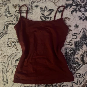 Vinröd linnetopp från Bershka XS - Säljer en vinröd linnetopp från Bershka i storlek XS. Toppen har smala axelband och en enkel, figurnära passform. Perfekt att styla med jeans eller kjol för en snygg look. Materialet är mjukt och stretchigt för extra komfort.