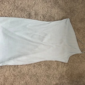 Ljusblå ribbad klänning med smala axelband - Supersnygg ljusblå klänning med smala axelband och ribbad struktur. Den har en kroppsnära passform och är ärmlös, perfekt för varma dagar. Tunt, stretchigt material som känns skönt mot huden och ger en clean look.