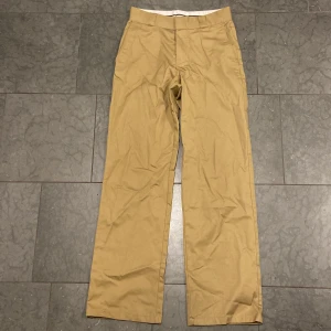 Beiga chinos från H&M Divided, stl 32 - Snygga beiga chinos från H&M Divided i storlek 32. Klassisk rak passform med bälteshällor, sidfickor och knäppning fram. Perfekta för en clean och avslappnad look. Tillverkade i mjuk bomull för skön känsla hela dagen.