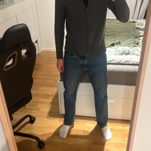 Levi's 501 blå jeans straight fit - Klassiska Levi's 501 jeans i blå denim med raka ben och normal passform. Byxorna har fem fickor, knappgylf och den ikoniska läderpatchen bak i midjan. Perfekta för dig som gillar en tidlös och avslappnad stil.