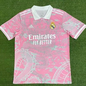Rosa Real Madrid fotbollströja Adidas - Snygg rosa Real Madrid fotbollströja från Adidas med drakmönster i ljusgrått. Tröjan har vit krage, korta ärmar och klubbmärke på bröstet. Perfekt för dig som vill sticka ut på planen eller på läktaren.