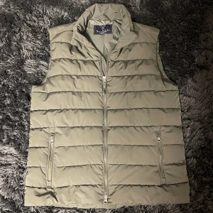 Olivgrön dunväst från Bondelid  - Snygg olivgrön dunväst från Bondelid med quiltad design och ståkrage. Västen har två dragkedjeförsedda fickor och hel dragkedja framtill. Perfekt för lager-på-lager och enkel att matcha med skjorta eller hoodie. Köptes för 1400 och är i ett väldigt bra skick!💯🔥