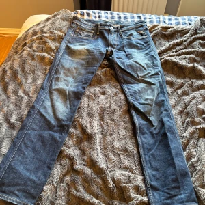 Blå Replay jeans straight fit - Säljer ett par klassiska blå jeans från Replay med raka ben och snygga kontrastsömmar. Jeansen har fem fickor, normal midja och är tillverkade i slitstarkt denim. Märkespatch bak i midjan och diskreta detaljer på bakfickorna.