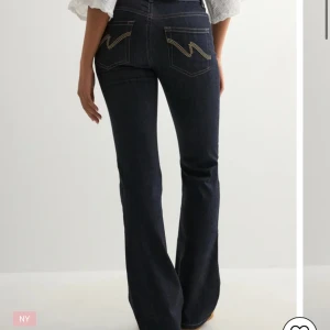 Mörkblå bootcut jeans med kontrastsömmar - Snygga mörkblå jeans med bootcut-modell och coola kontrastsömmar på fickorna. De e klippta långst ner o innerbenslängden e ca 67cm. Använda endast en gång