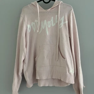Ljusrosa stickad hoodie Odd Molly - Superfin ljusrosa stickad hoodie från Odd Molly med vit logga framtill. Tröjan har huva med snörning, magficka och ribbade muddar. Snygg loose passform och långärmad. 