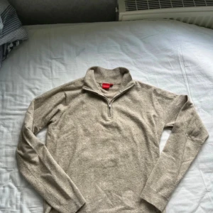 Beige half zip-tröja från RYVLS - Säljer en beige långärmad tröja från RYVLS med half zip-dragkedja i halsen. Tröjan är i mjukt material och har en enkel, stilren design som passar perfekt till höst och vinter. Perfekt för dig som gillar en clean och avslappnad look.