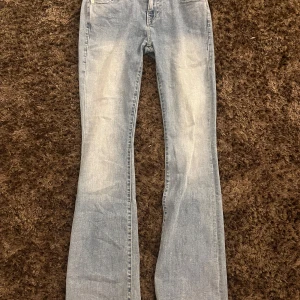 Ljusblå bootcut jeans från True Religion - Säljer ett par ljusblå low waidt jeans från True Religion med bootcut passform. Jeansen har klassiska fickor med lock och silverfärgade knappar med logga. Snygga sömmar och detaljer på bakfickorna. Perfekta för dig som gillar en retro vibe. Säljer pågrund av att dom ej kommer till andvändning. 